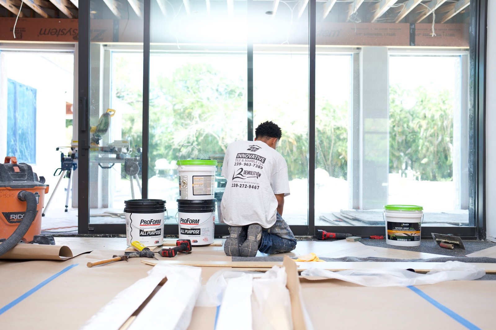 An Innovative Tile & Marble crew member working on a protected floor, with rosin paper, taped seams and a shop vacuum for dust control.